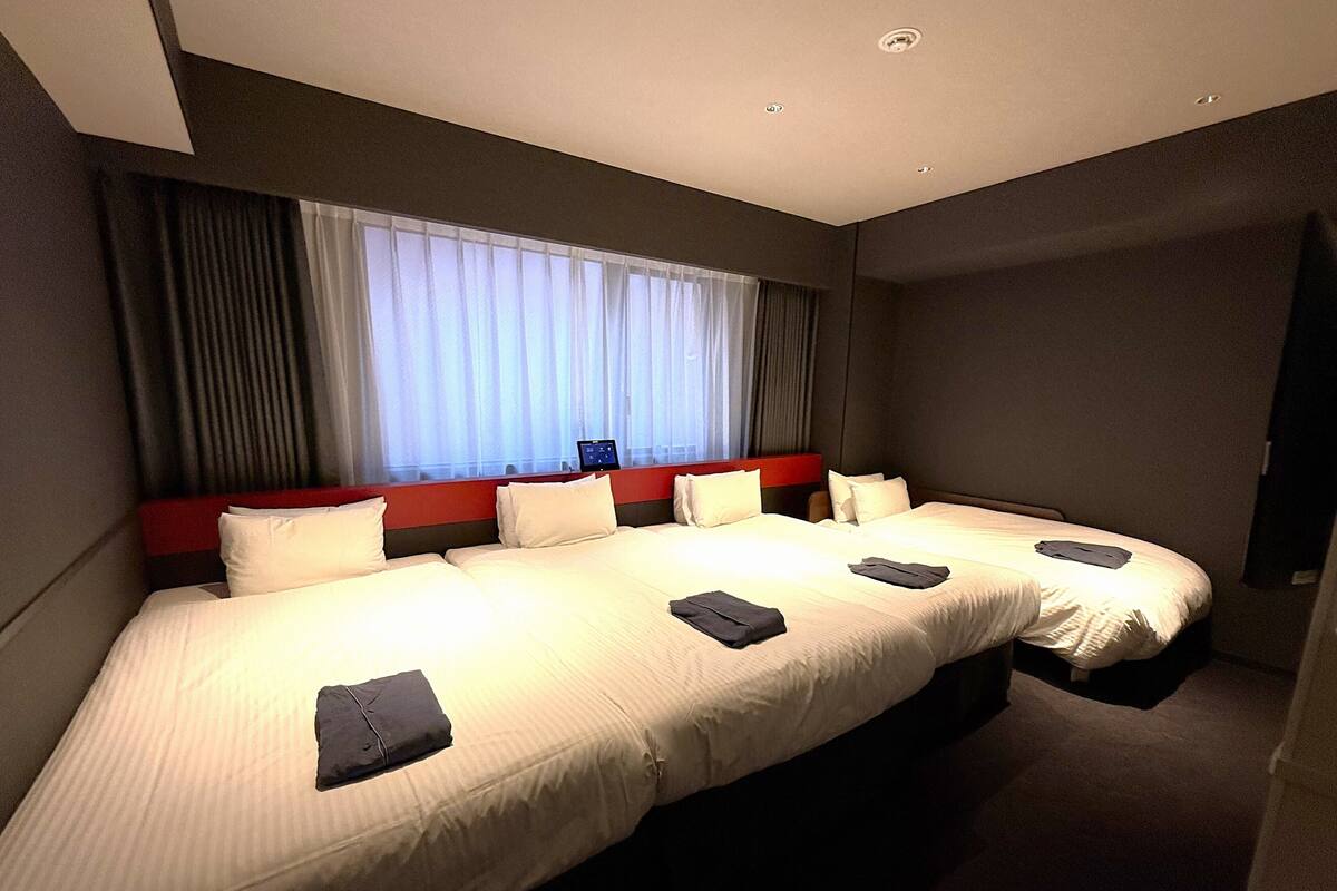 Ein Hotelzimmer mit einem großen Bett, einem Schreibtisch und einem Fenster mit Vorhängen.