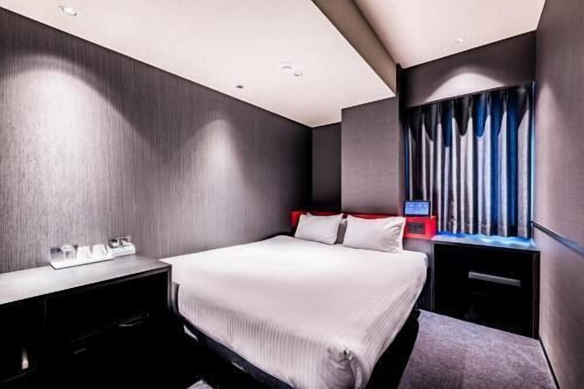 Ein modernes Hotelzimmer mit einem großen Bett, einem Schreibtisch und einem Fernseher.