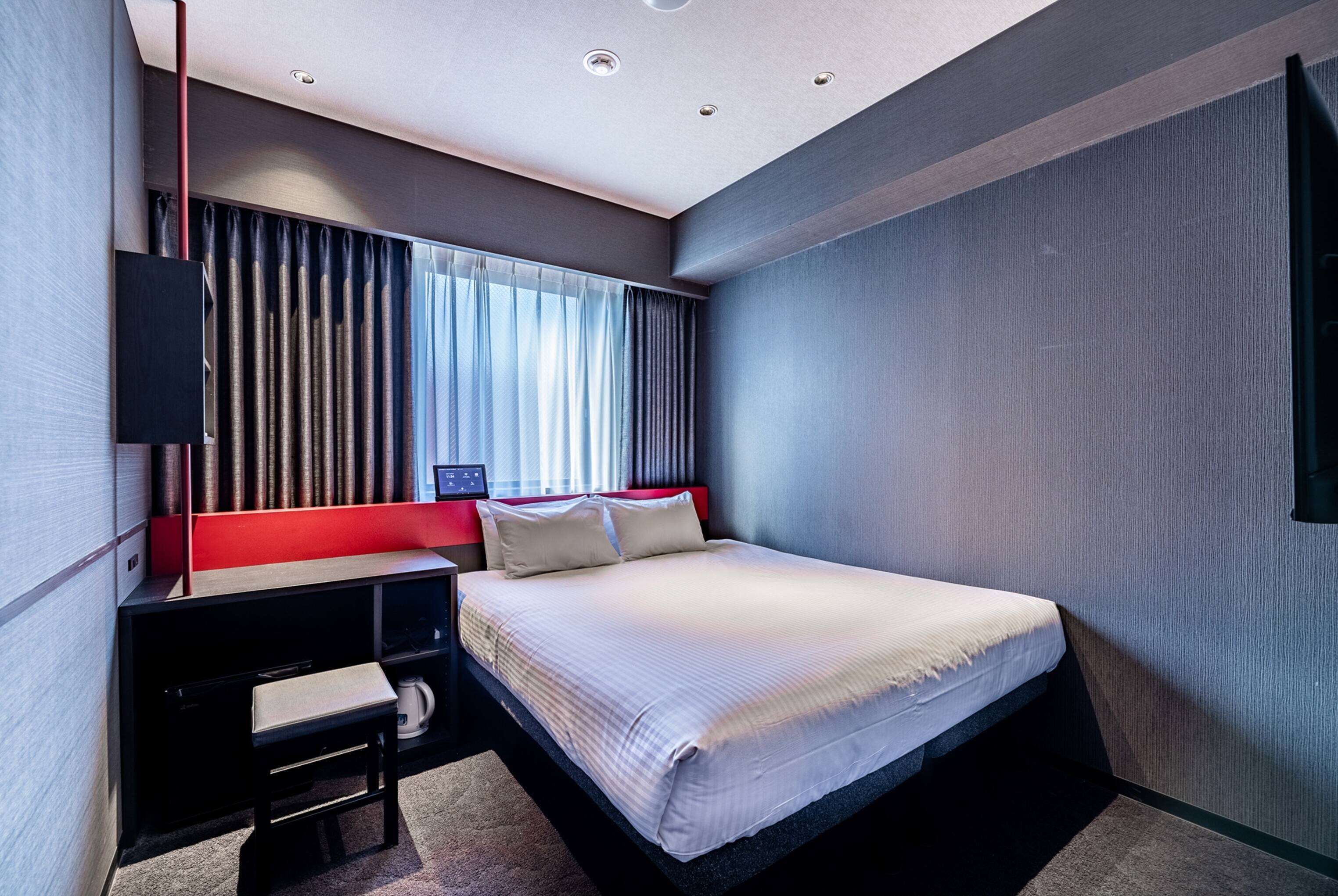 Una habitación de hotel moderna con cama, escritorio y televisor.