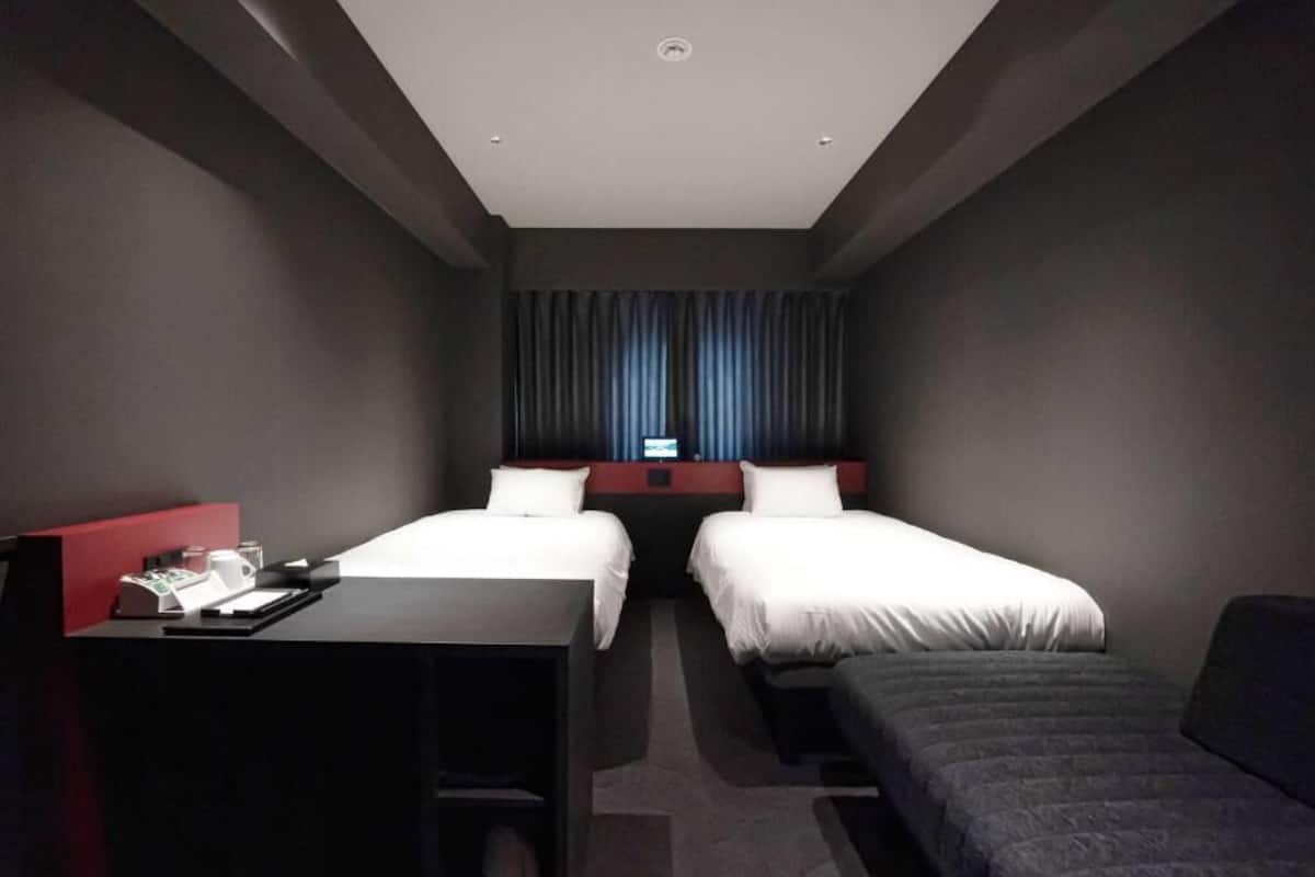 Une chambre d’hôtel avec deux lits, un bureau et un petit canapé.