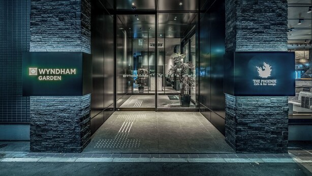 The entrance to Wyndham Garden and The Phoenix Cafe & Bar Lounge, featuring glass doors and a stone facade. - Wyndham Garden Sapporo Odori (Sapporo)