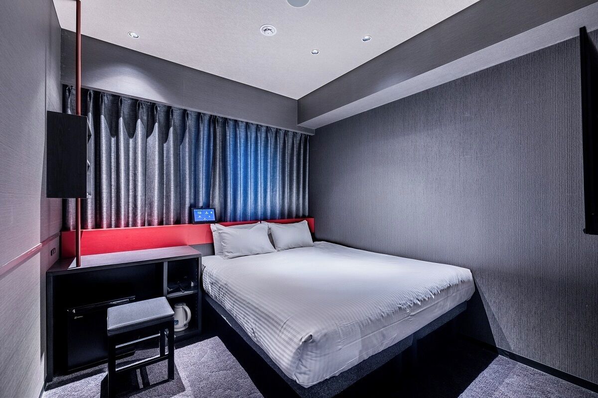 A modern hotel room with a bed, a desk, and a TV.