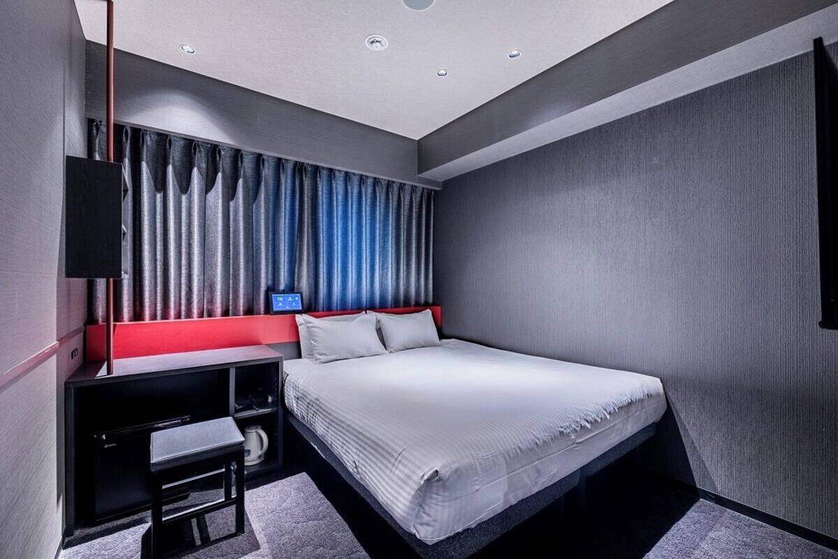 Ein modernes Hotelzimmer mit Bett, Schreibtisch und Fernseher.