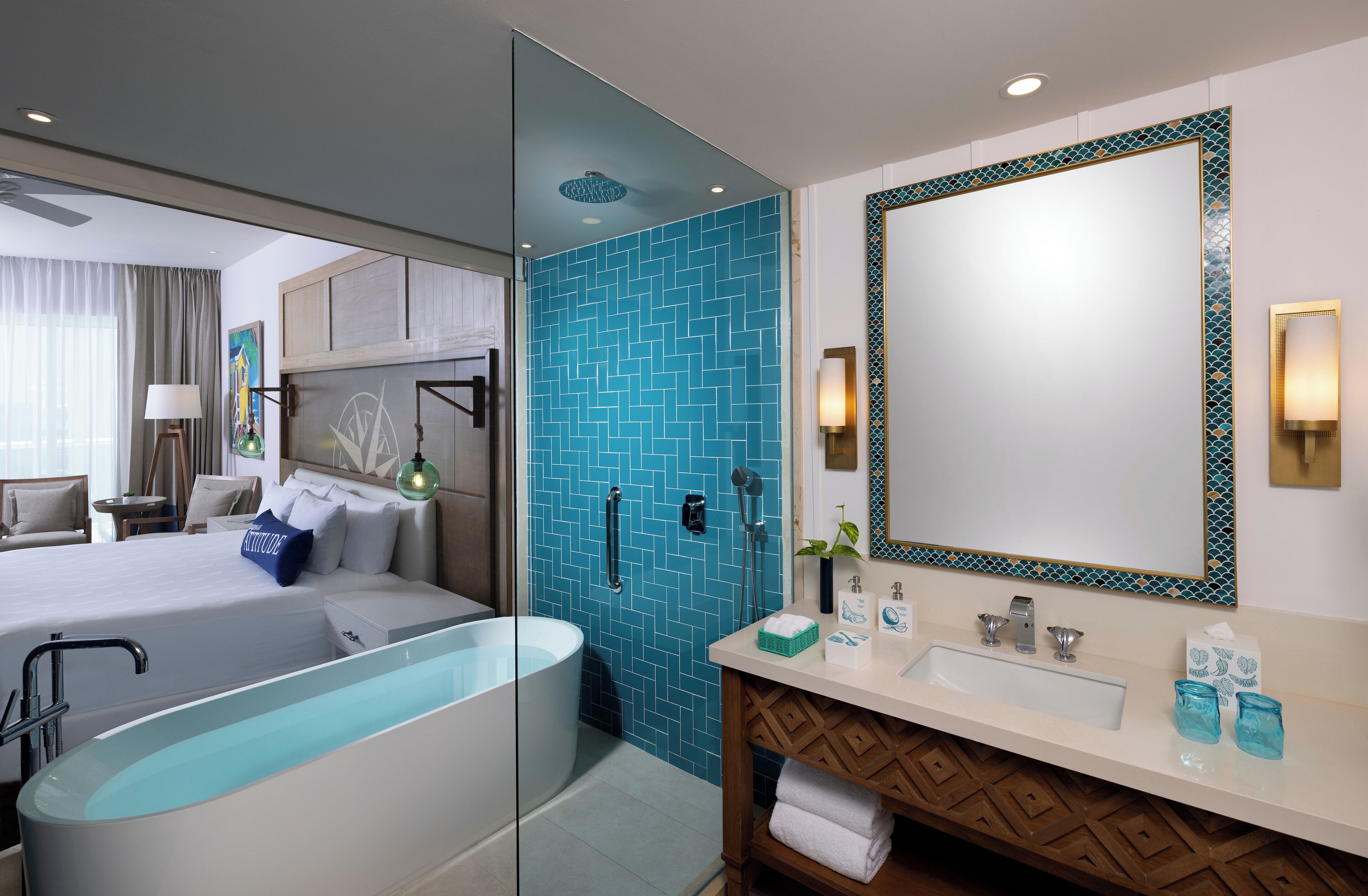 Une chambre d’hôtel moderne dotée d’un grand lit, d’une douche en verre, d’un grand miroir et d’une coiffeuse avec un lavabo et un porte-serviettes.