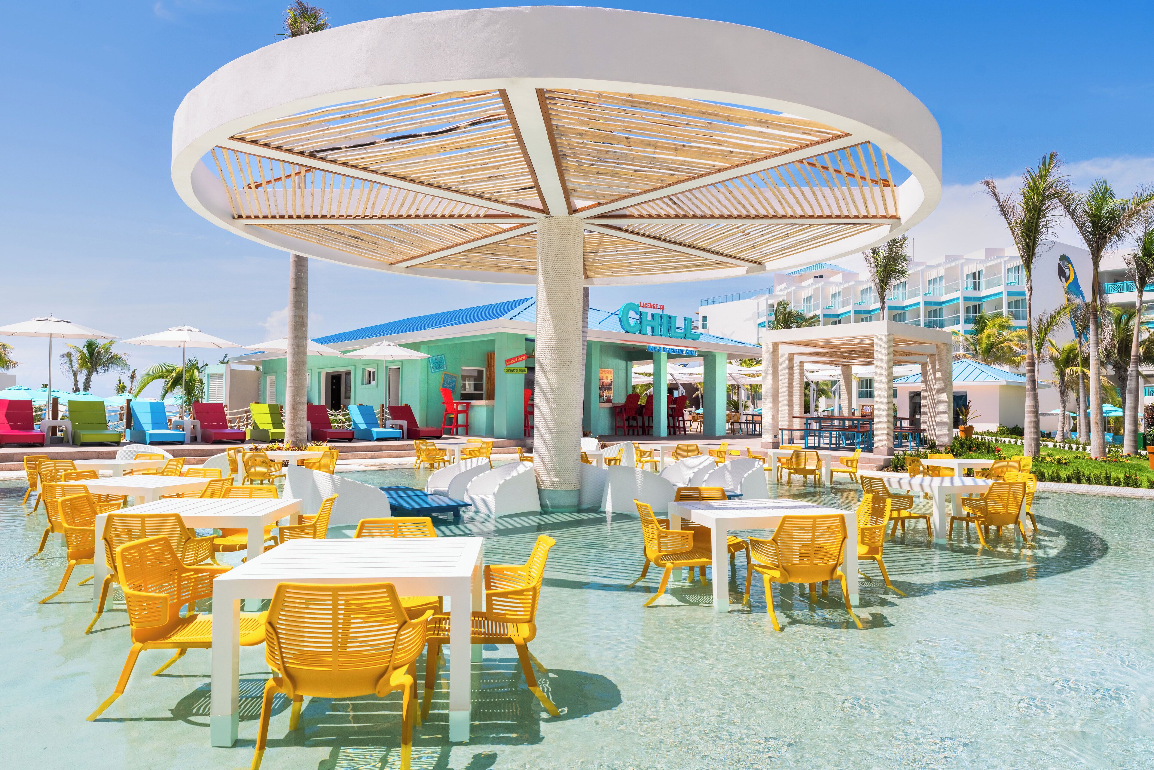 A poolside area with yellow chairs and tables, a large umbrella structure, and a building labeled "Chill".