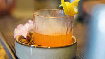 Un verre contenant un liquide ambré, garni d’une tranche de citron et posé sur un sous-verre, lui-même placé sur une surface texturée.