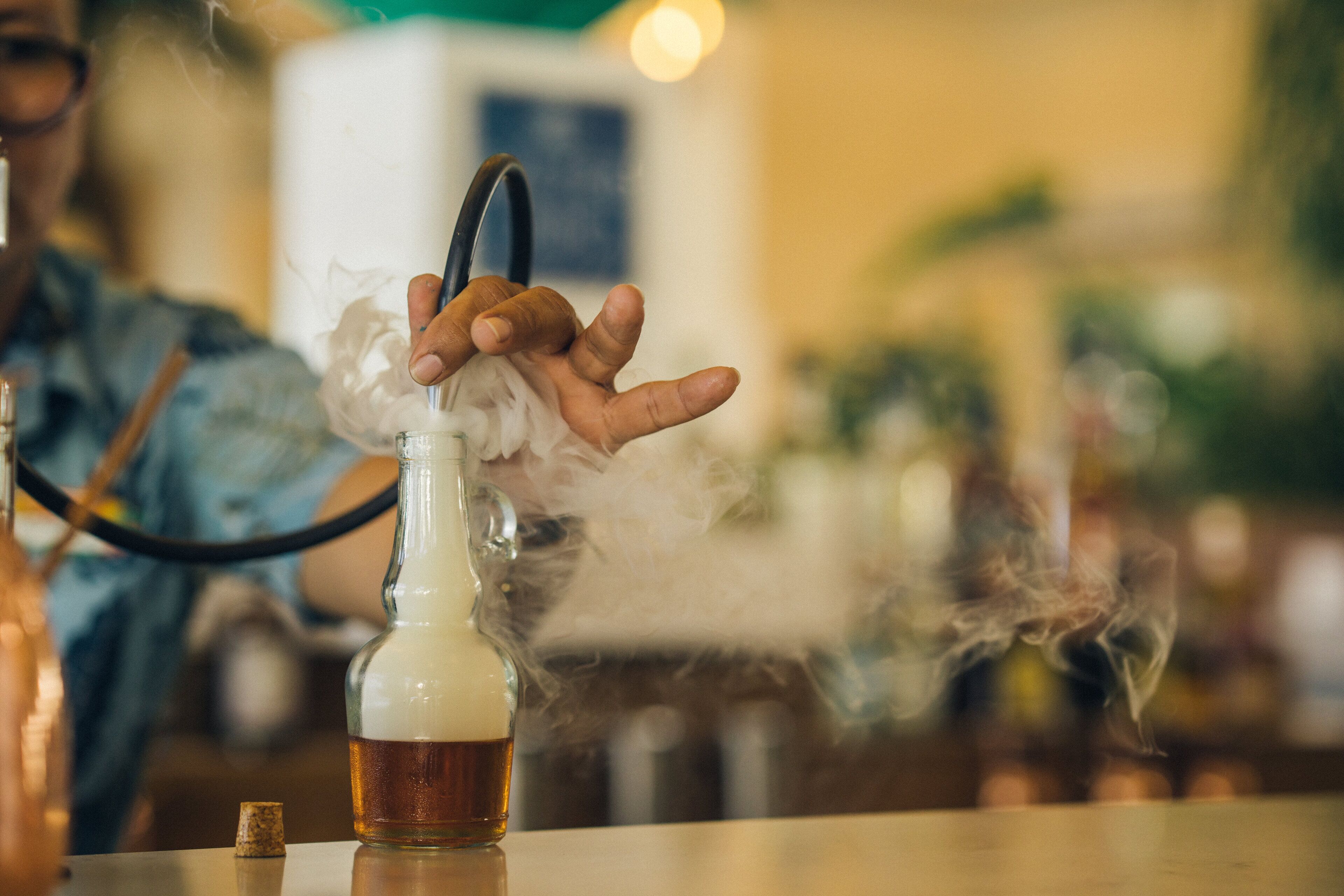 A person holding a hookah with smoke rising from it.