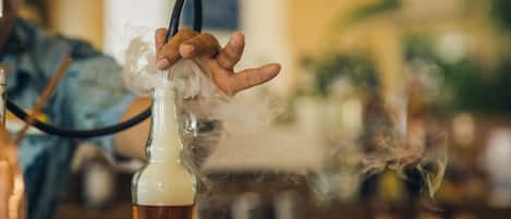 A person holding a hookah with smoke rising from it.