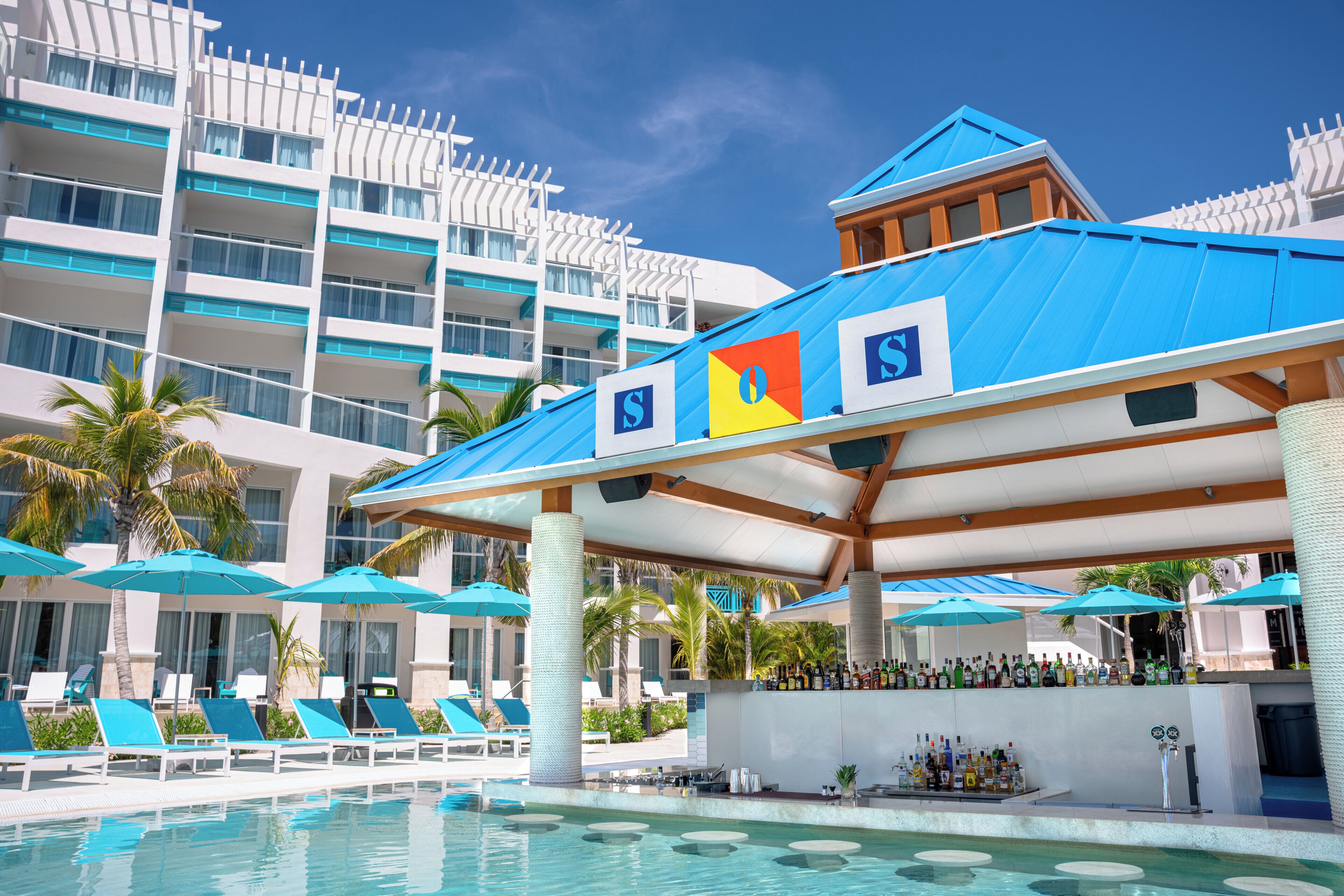 Un complexe hôtelier doté d’une piscine, de chaises longues, de parasols et d’un espace bar.