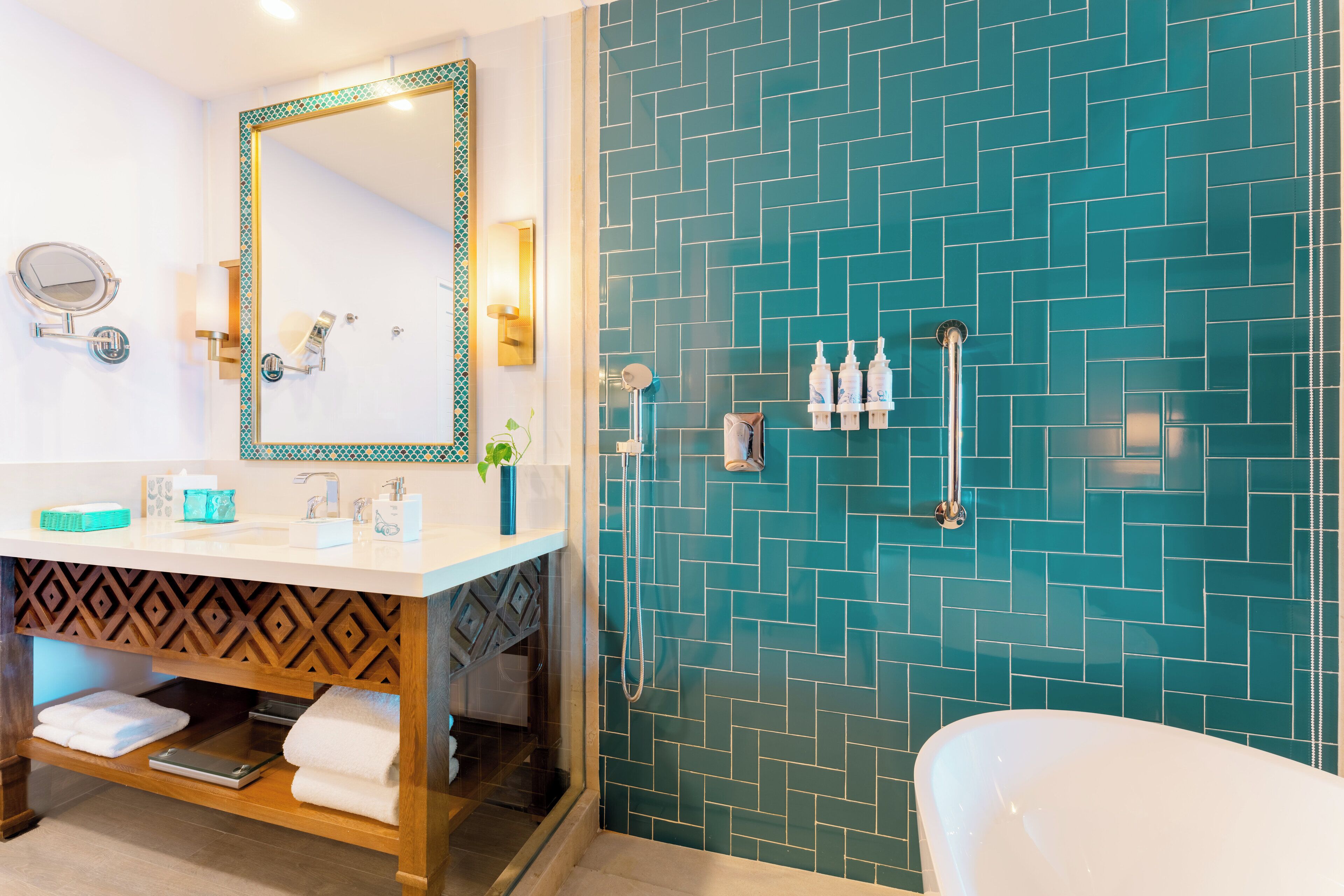 Une salle de bain avec un lavabo blanc, un miroir, un porte-serviettes et un espace douche avec un mur recouvert de carreaux bleus.