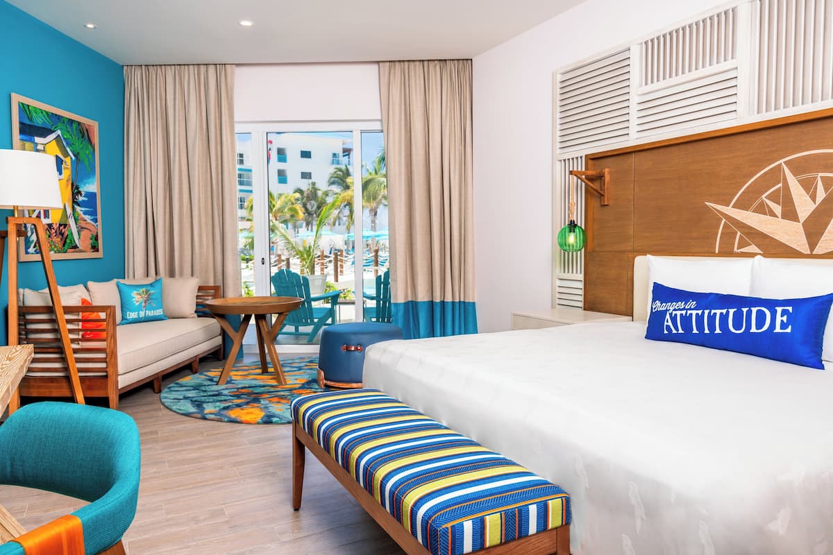 A hotel room with a bed, a sofa, a bench, a table, and a painting.