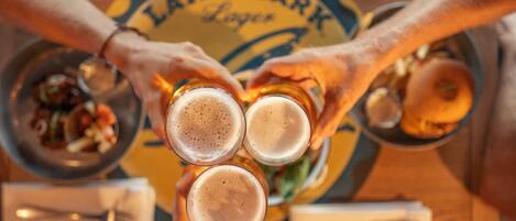 Three people toasting with glasses of beer in front of a sign that reads "LAND SHARK Lager."