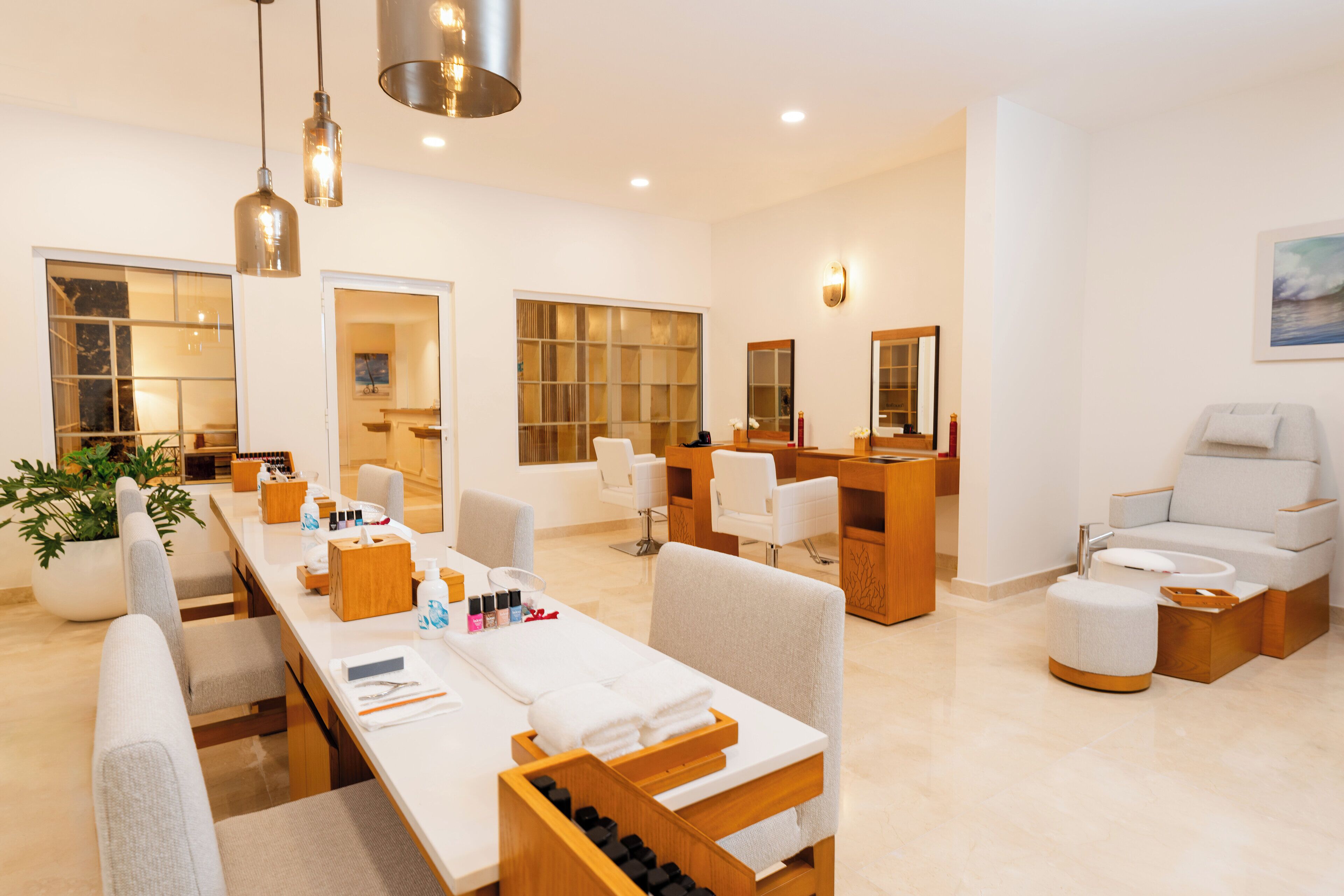 A modern spa room with a long reception desk, multiple seating areas, and a large window providing natural light.