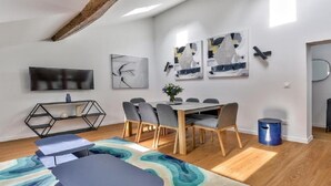 A modern living room with a dining area, a TV, abstract art, and a minimalist design. - A paradise for food lovers- An essence of French gastronomy in Montrogueil (Paris)