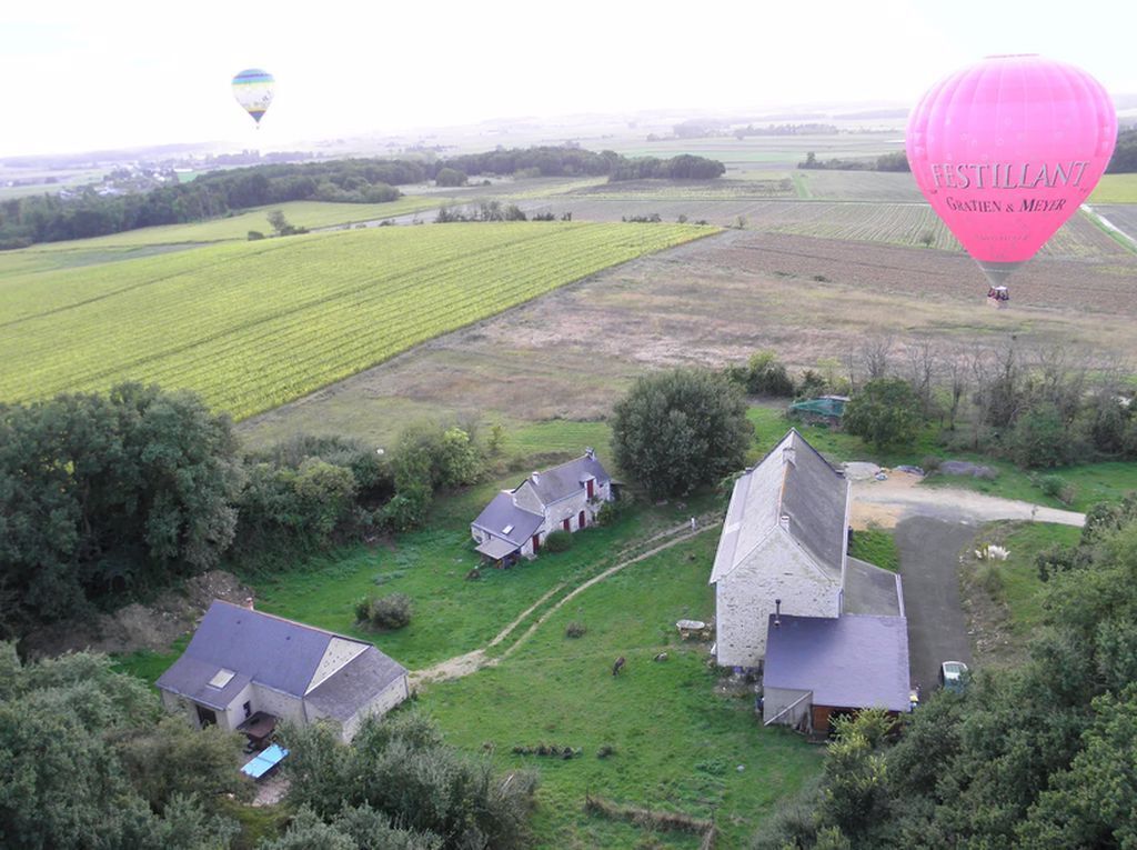 An aerial view of a rural area with fields, a stone building, and two smaller houses.