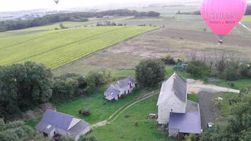 An aerial view of a rural area with fields, a stone building, and two smaller houses.
