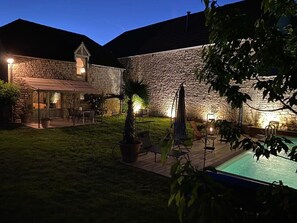A stone building with a pool, outdoor seating, and a well-lit patio area. - Village House with Private Pool – Gite-Loubaribas (Condat)