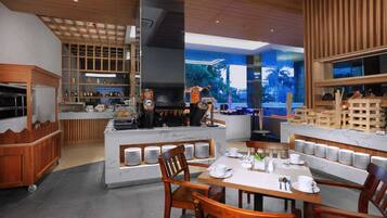 A modern restaurant with a central island, wooden furniture, and a view through large windows.