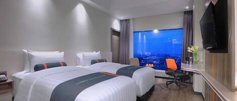 Habitación de hotel con dos camas, un escritorio, un televisor y vistas a la ciudad.