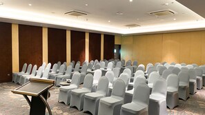 A conference room with rows of chairs and tables, equipped with ceiling lights and a carpeted floor.