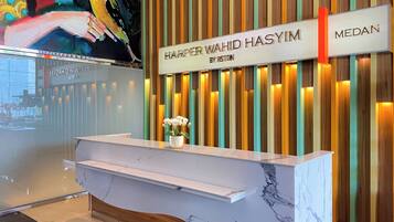 A hotel reception desk with a marble top and a sign above it that reads "Harper Wahid Hasiyim by Bston".