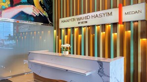 En hotellreception med en marmorskiva och en skylt ovanför som visar texten: ”Harper Wahid Hasiyim by Bston”.