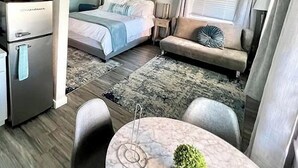 Ein kompaktes Hotelzimmer mit Bett, einer Couch, einem Esstisch und einer Küchenzeile.
