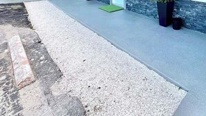 Ein moderner Hotel Eingangsbereich mit überdachtem Gang, Topfpflanzen und einer Steinfassade.