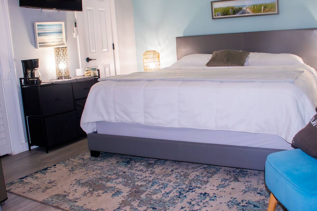 A neatly arranged bedroom with a bed, bedside tables, a desk, and a chair.