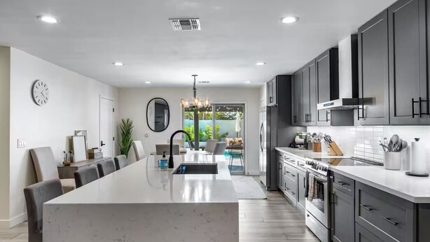A modern kitchen with a large island, dark grey cabinets, and a view to a patio.