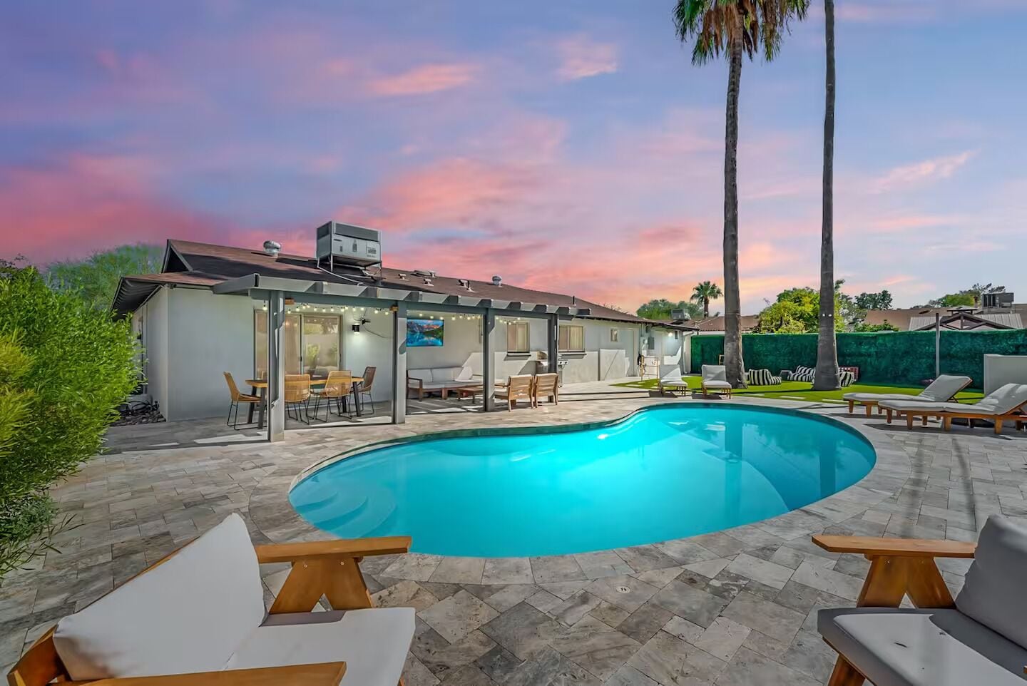 Une maison moderne dotée d’une piscine, d’un espace salon extérieur et d’un patio couvert.