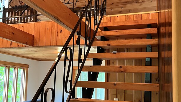 Eine Holztreppe mit Metallgeländern, die zu einem Erker führt.