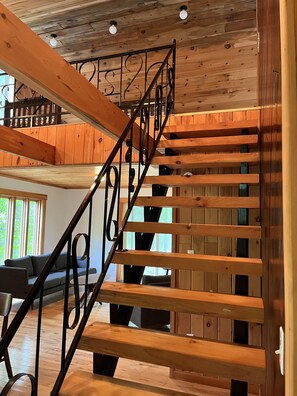 A wooden staircase with metal railings leading to a loft area.