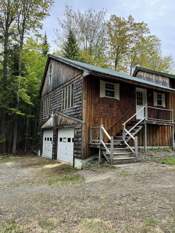 A rustic wooden cabin with a front porch and a staircase leading to the entrance.