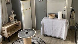 Een kleine slaapkamer met een bed, een tafeltje, een televisie en een koelkast.