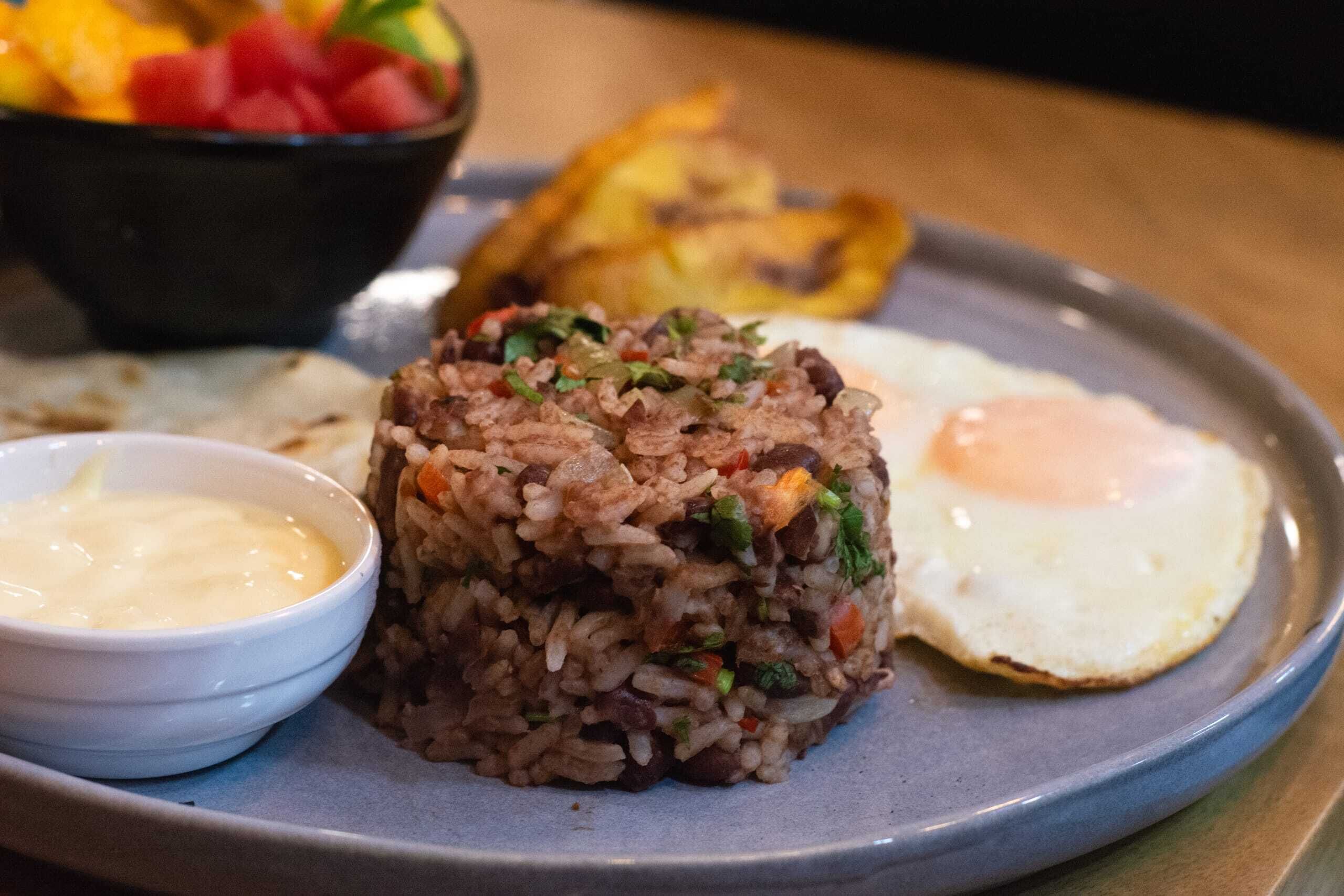 Un plato de arroz frito, un huevo frito y un recipiente pequeño con salsa.