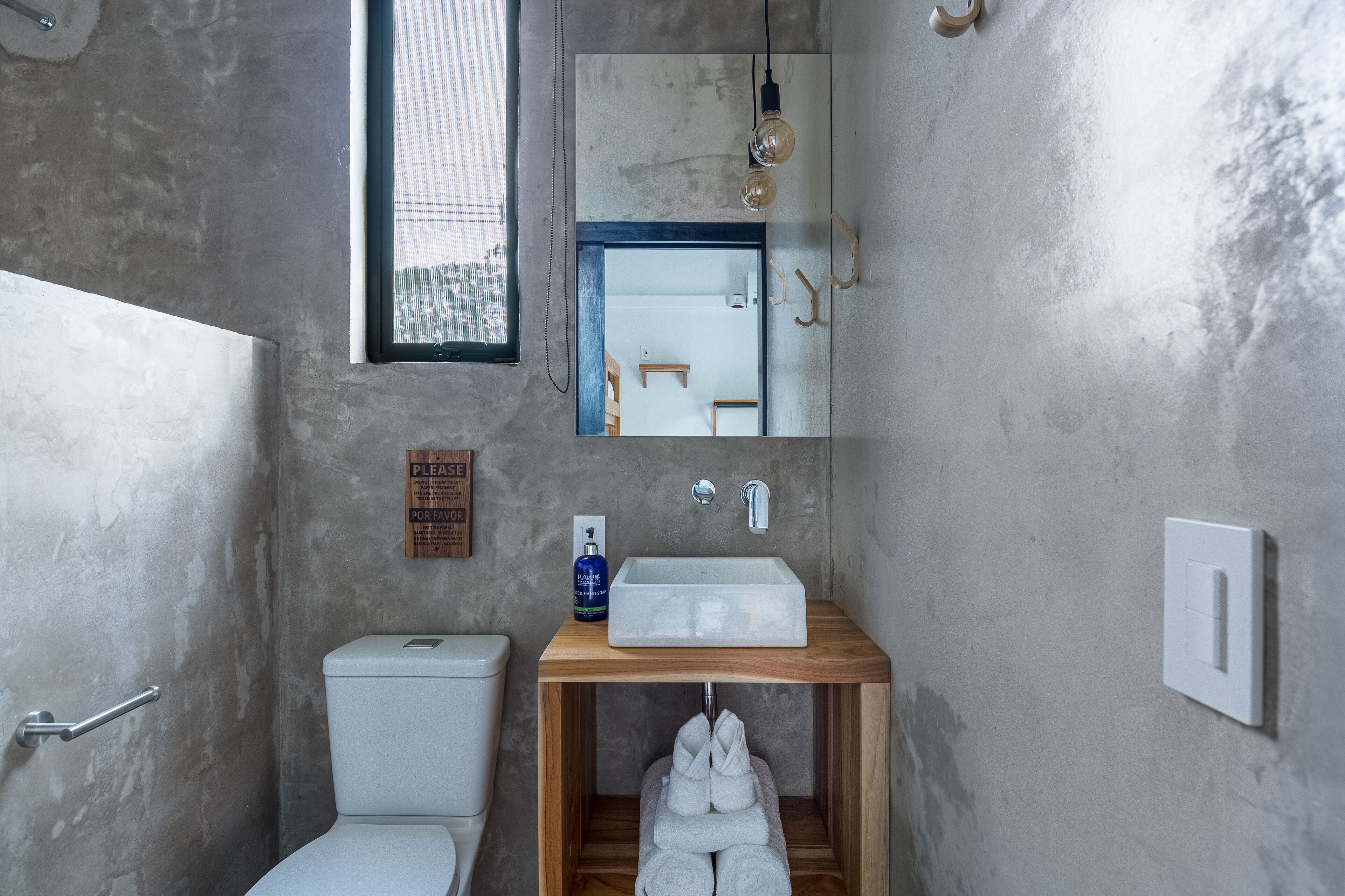 A bathroom with a white toilet, a wooden vanity with a sink, and a towel rack.