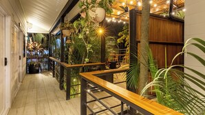 Un couloir doté d’un plancher en bois, d’un banc en bois et de plantes suspendues.
