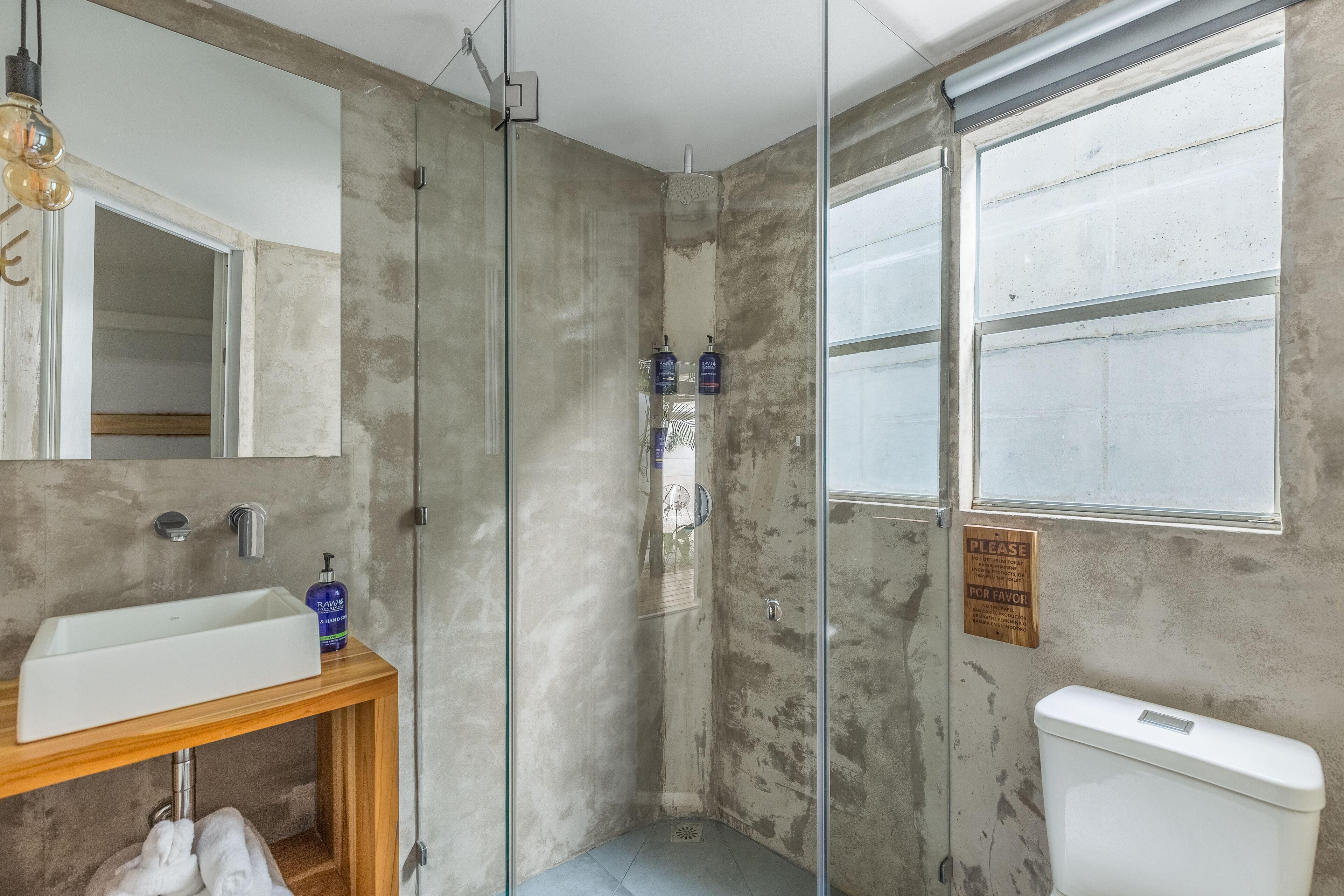 Ein Badezimmer mit einem weißen Waschbecken, einer Glasdusche und einer Toilette.