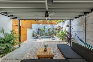 Un patio exterior moderno con piscina, mobiliario y diversas plantas.
