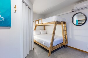 A bunk bed with a wooden frame and white bedding, a round mirror on the wall, and a door with a white frame.