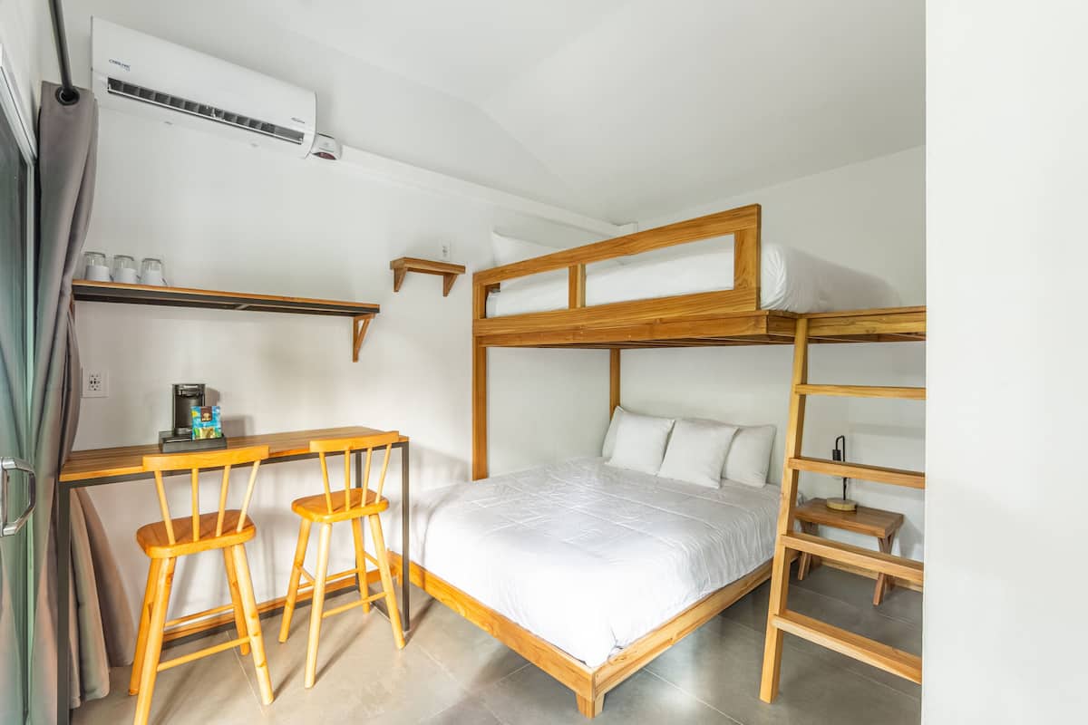 Habitación con literas, un escritorio y dos taburetes de madera.