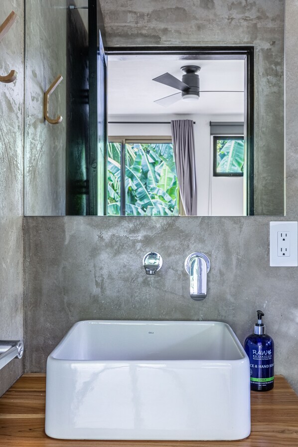 Un baño con un espejo grande, una bañera blanca, un ventilador de techo y una ventana con cortinas.
