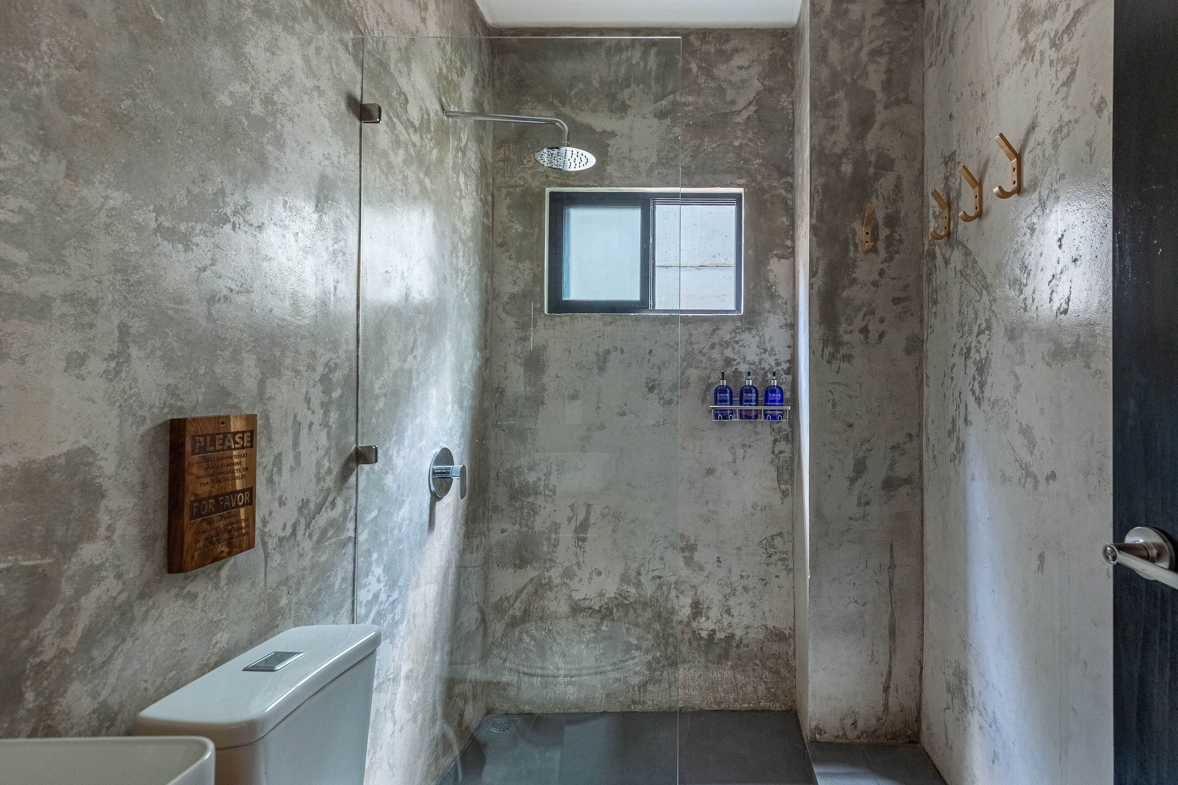 A small, enclosed shower area with a window, a sign on the wall, and a towel rack.