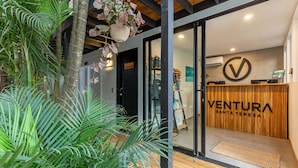 Un espace d’accueil avec un comptoir de réception en bois, un grand logo et une vue sur l’intérieur.