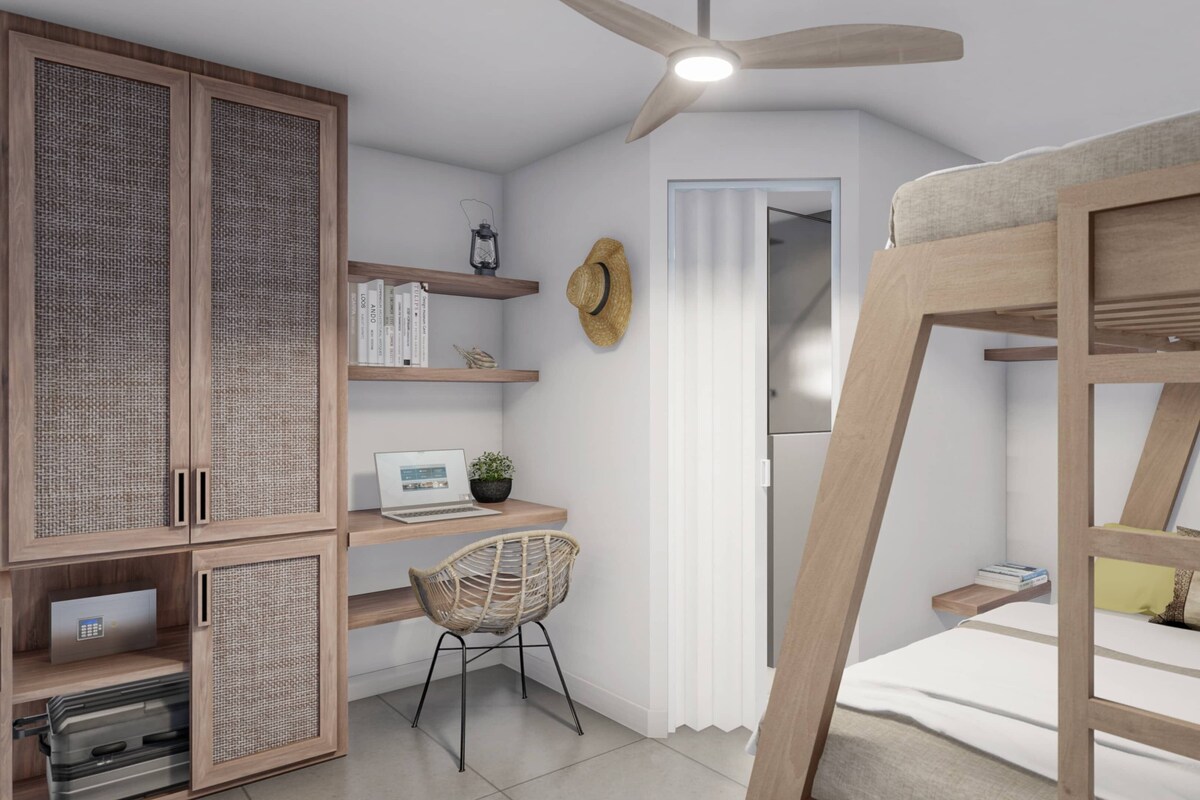 A bedroom with a bunk bed, a desk with a computer, a chair, a wardrobe, and a ceiling fan.