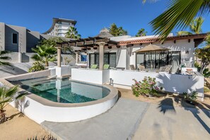A modern pool area with a circular pool, lounge chairs, and a pergola.