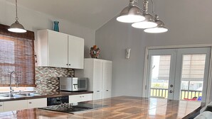 Una cocina moderna con una isla grande, armarios blancos y un comedor con sillas grises.