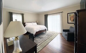 Une chambre d’hôtel avec un lit, un bureau doté d’une lampe, une chaise et une grande armoire en bois.