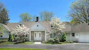 A two-story house with a central entrance, a garage on the right, and a well-maintained lawn. - Exquisite, first floor stone ranch Gettysburg large kitchen/living area - quiet  (Gettysburg)